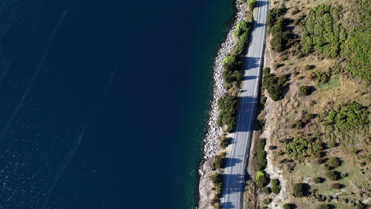 Cars Driving On The Road Along Lake Hawea In South Island, Otago, New Zealand. - aerial shot