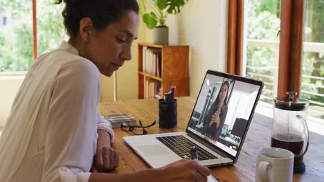 Afroamerikanische-Frau-Macht-Sich-Notizen,-Während-Sie-Zu-Hause-Einen-Videoanruf-Auf-Dem-Laptop-Führt