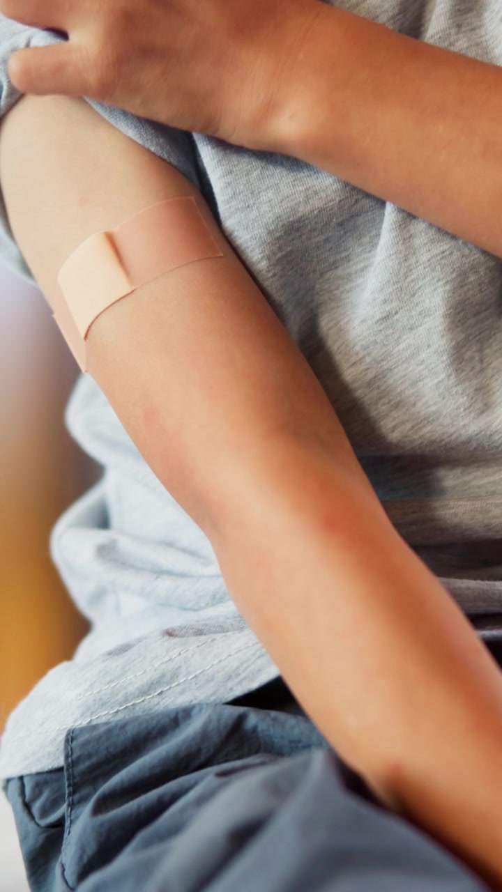 Child with Adhesive Bandage on Arm After Vaccination