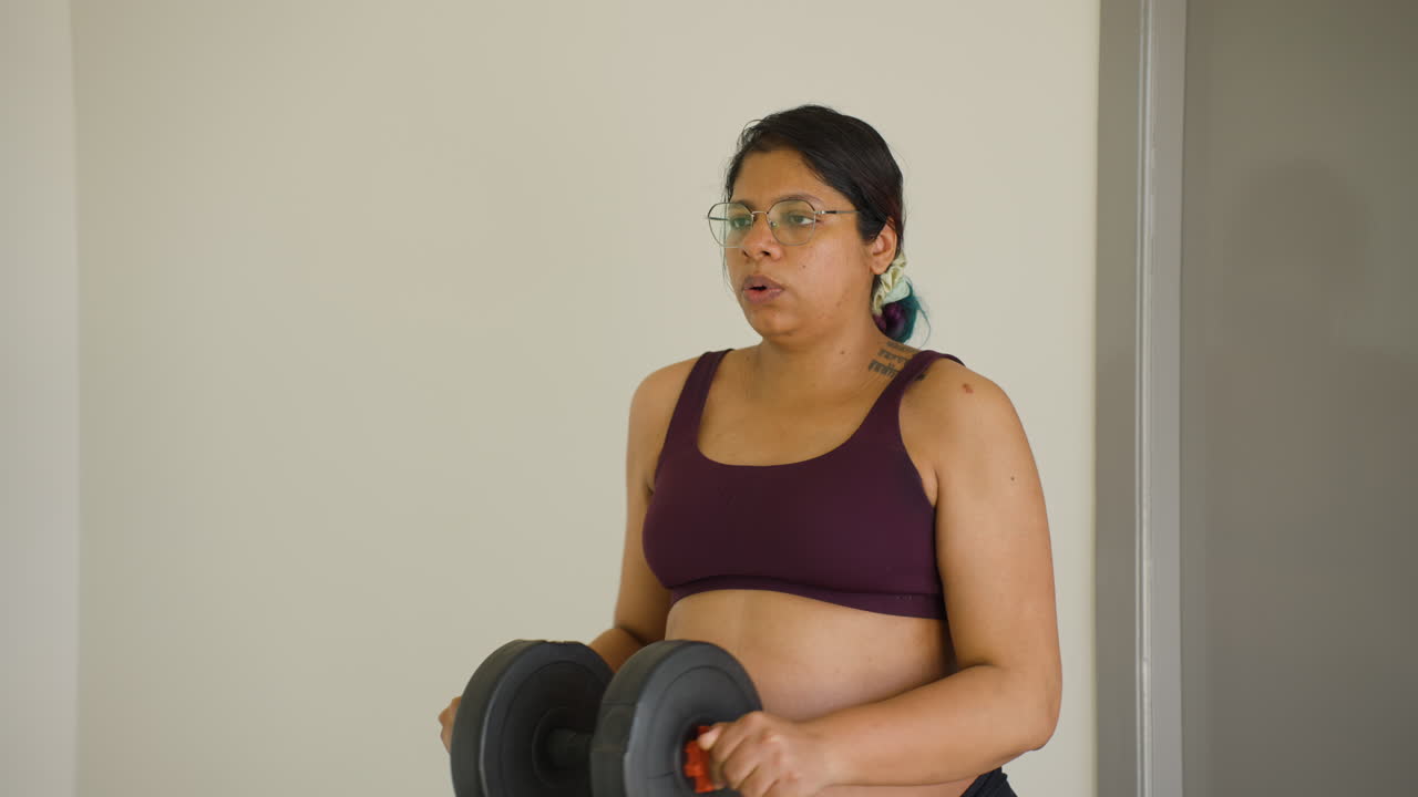 Mujer india embarazada levantando pesas, cuidando su cuerpo durante el tercer trimestre de gestación.