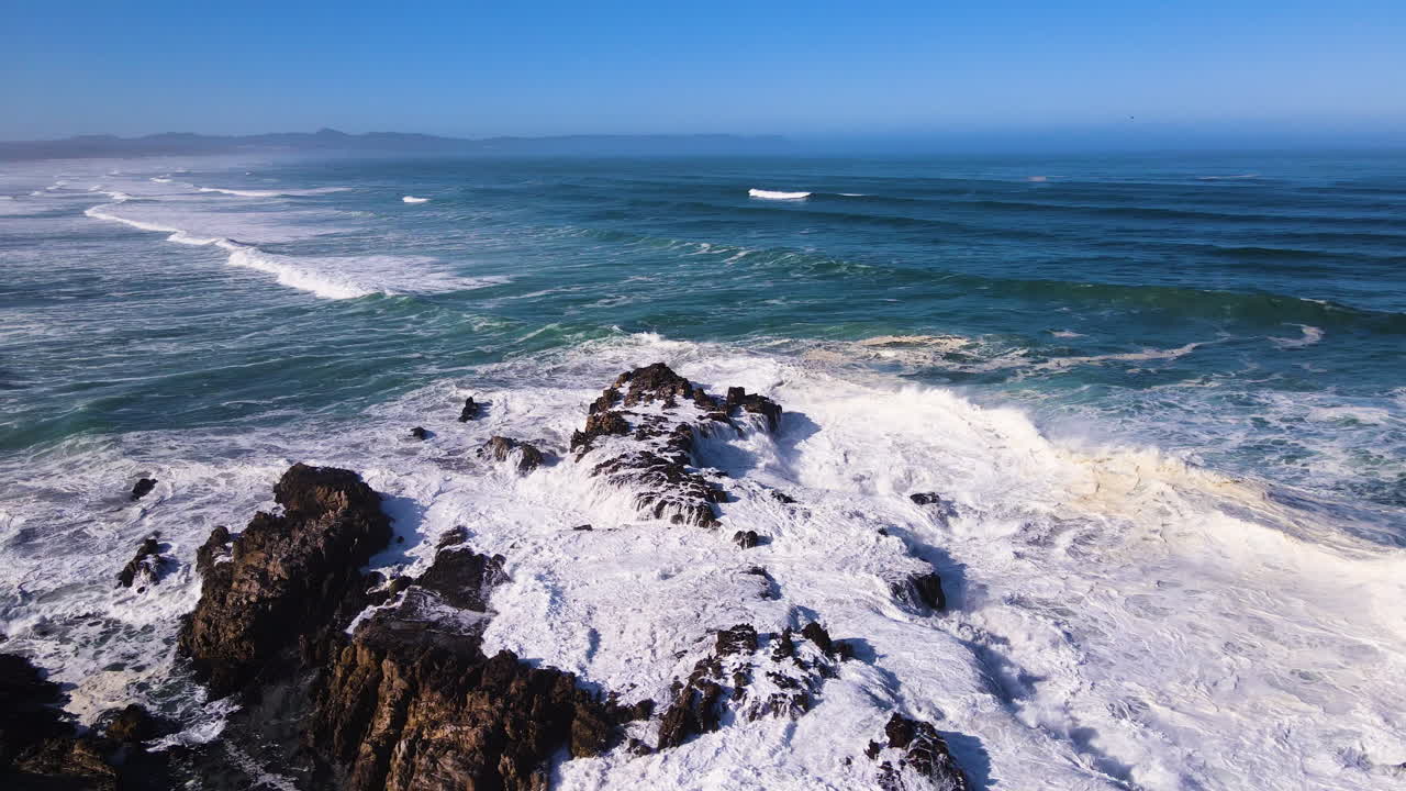 olas rompiendo contra rocas irregulares en la costa - océano tumultuoso