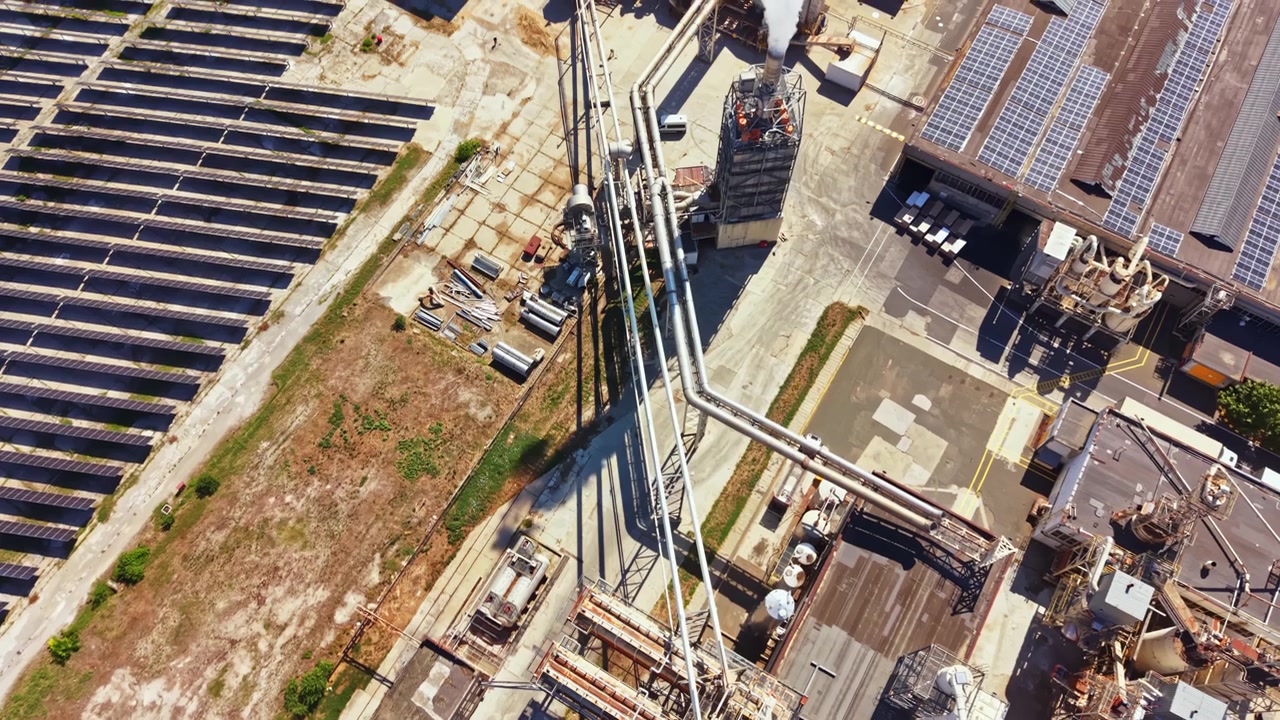 Vista aérea de instalación industrial con tuberías y paneles solares en una zona concurrida a plena luz del día