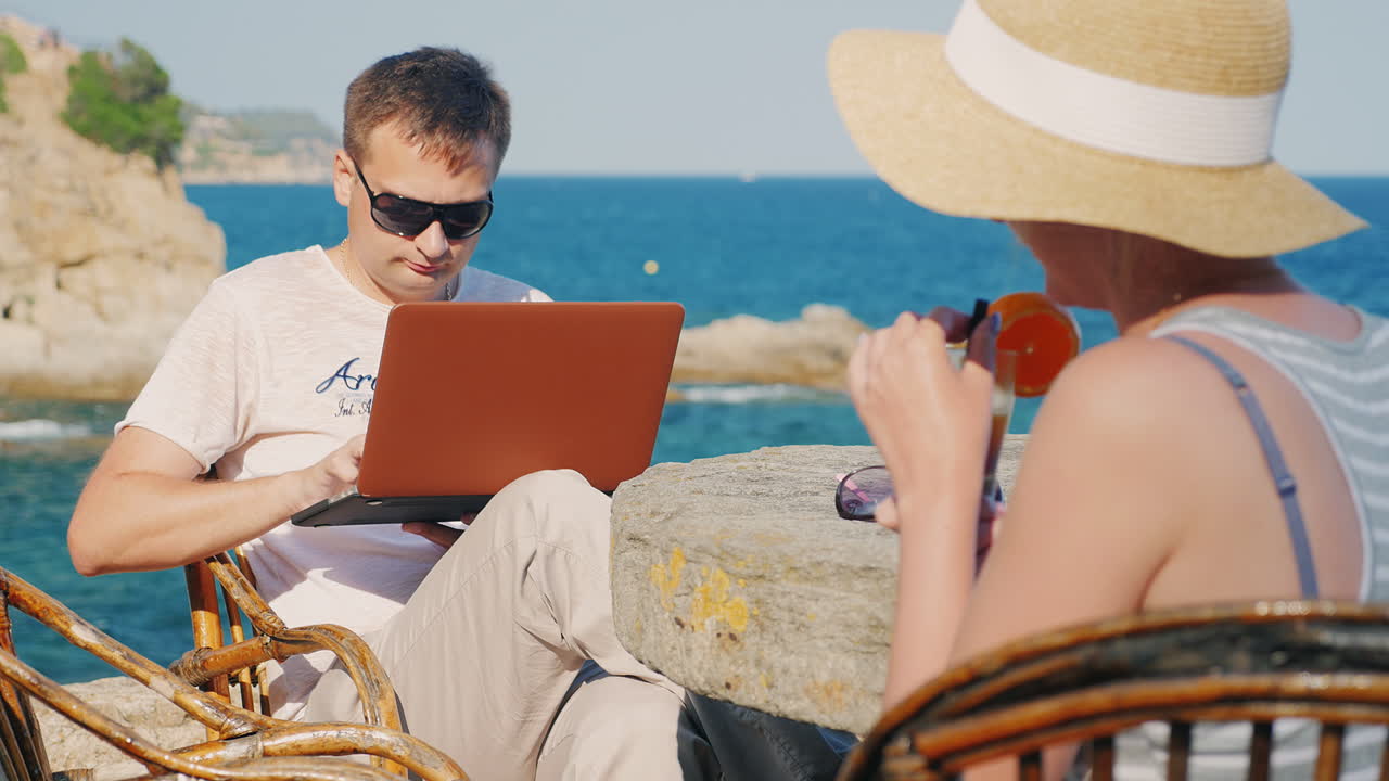 칵테일을 마시는 리조트 여성의 커플 랩탑으로 작업하는 남자