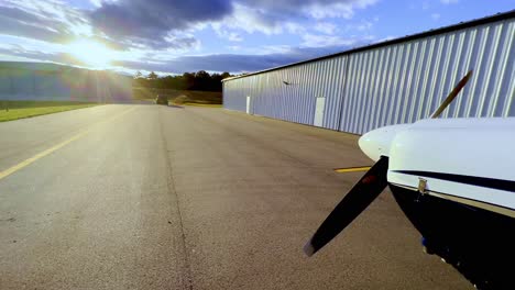 Schwenk-Von-Der-Untergehenden-Sonne-Zur-Stütze-Der-Piper-Cherokee-180-Auf-Dem-Rollfeld-Vor-Dem-Hangar