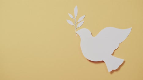 close up of white dove with leaf and copy space on yellow background