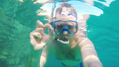 diver makes selfie waving at the camera - underwater