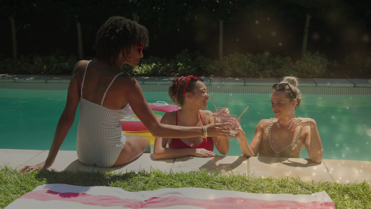 Three Happy Young Women Talking and Laughing by the Swimming Pool