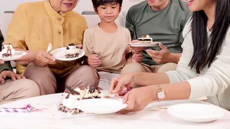 a joyful family gathering with grandparents, parents, and child enjoying cake in a festive setting