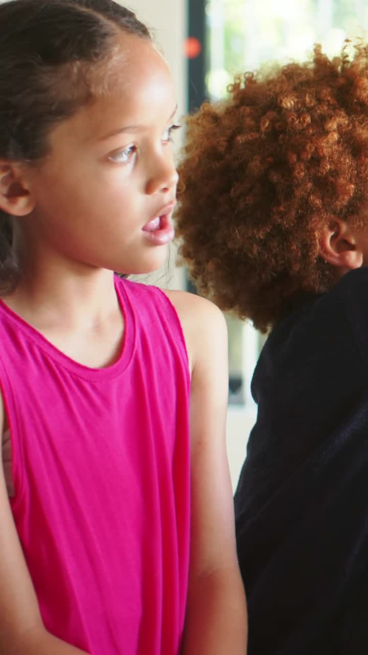 Vertical video: Call, girl in pink top turning at home window with pots as boy entering, copy space