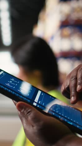vertical video close up of black woman monitoring e-commerce activity on tablet