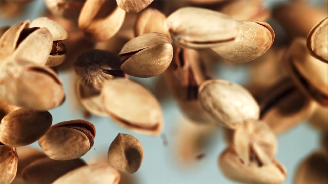 Super Slow Motion of Pistachios Falling Against a Light Blue Background