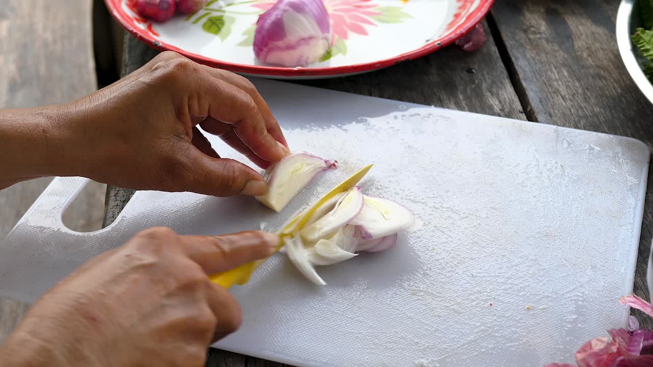 Finely slicing small onion on white chopping board