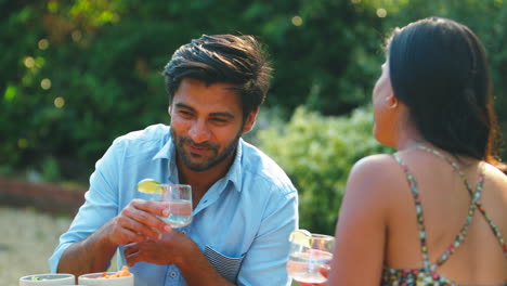 pareja comiendo comida al aire libre con bebidas frías en el jardín de verano en casa juntos