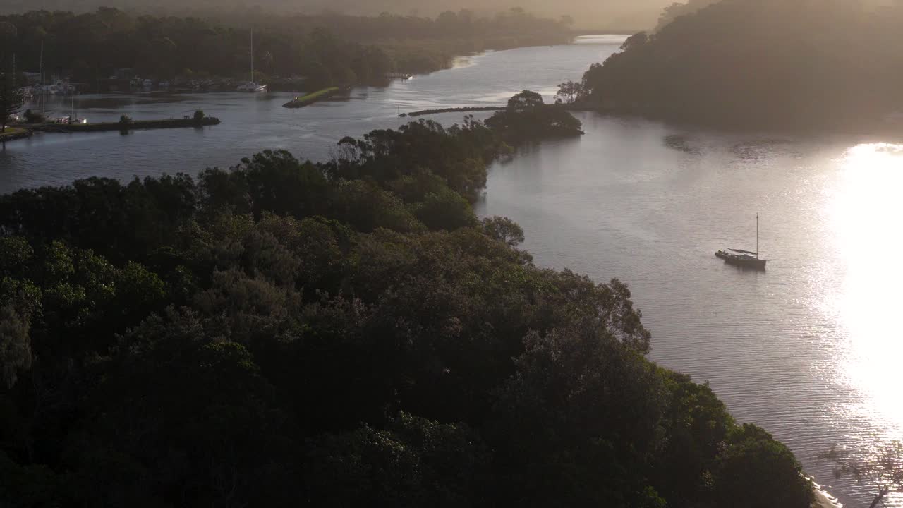 A tranquil river scene with a boat navigating through lush greenery under soft, golden sunlight