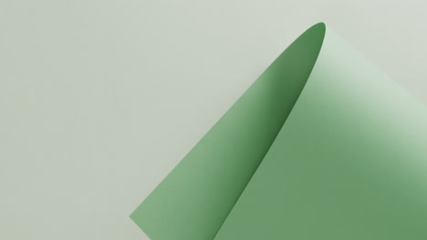 Close-up-of-green-rolled-piece-of-paper-on-white-background-with-copy-space-in-slow-motion