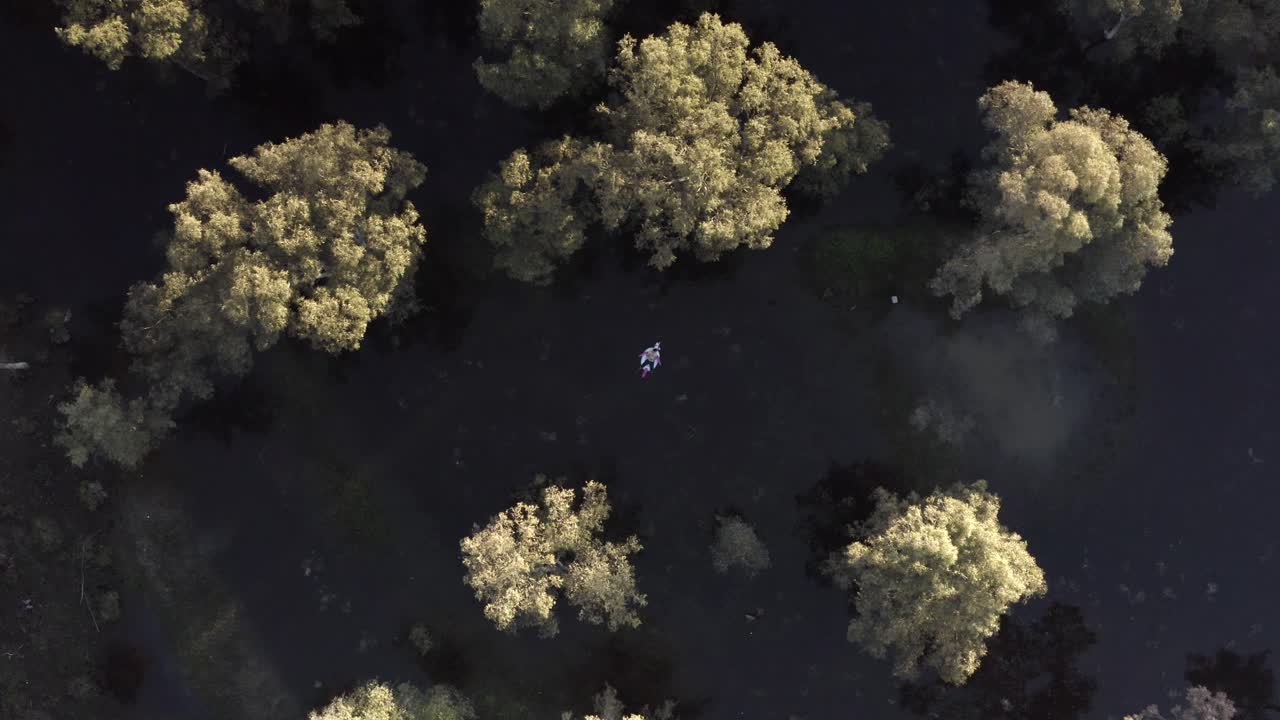 홍수 에 싸인 숲 에서 카야크 를 타고 있는 사람