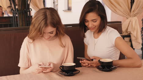 two women friends enjoying coffee and smartphones