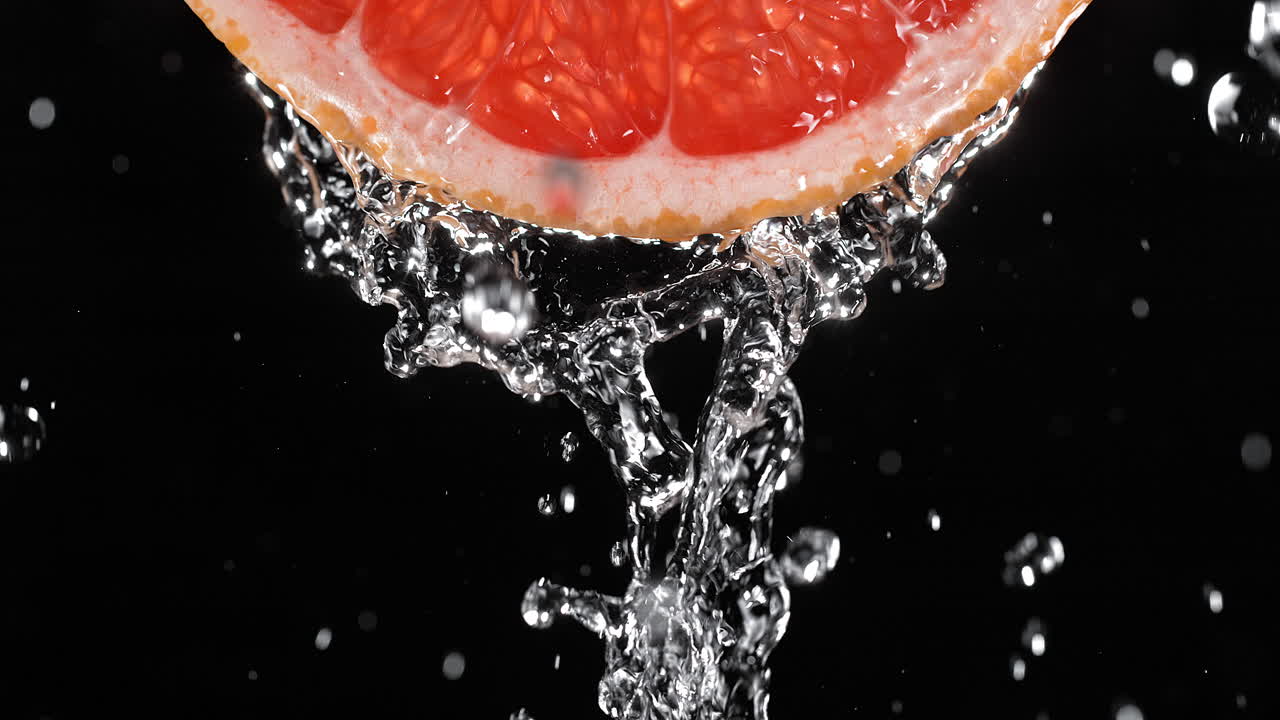 una rebanada de pomelo vertida con agua en cámara lenta y macro sobre fondo negro
