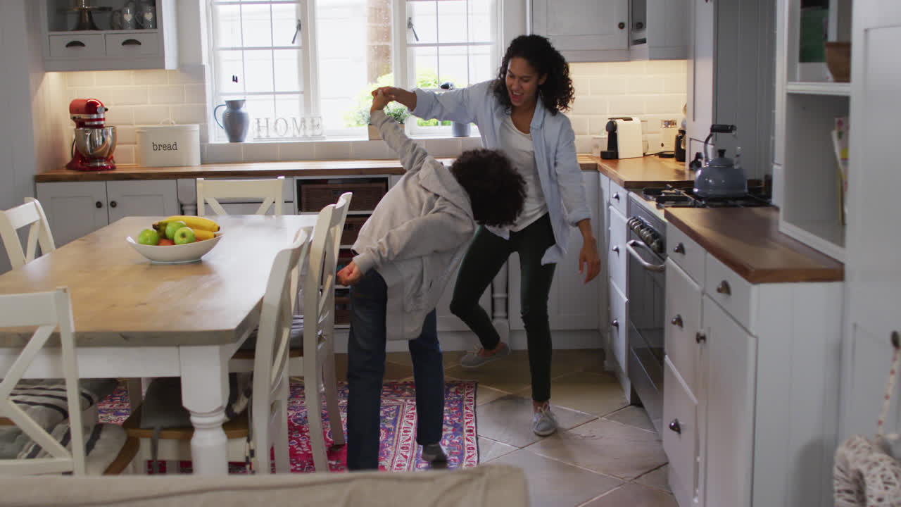 Mixed race lesbian couple and daughter dancing in kitchen