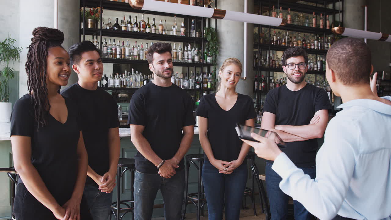 gerente de restaurante femenino con tableta digital dando al equipo hablar con el personal de espera