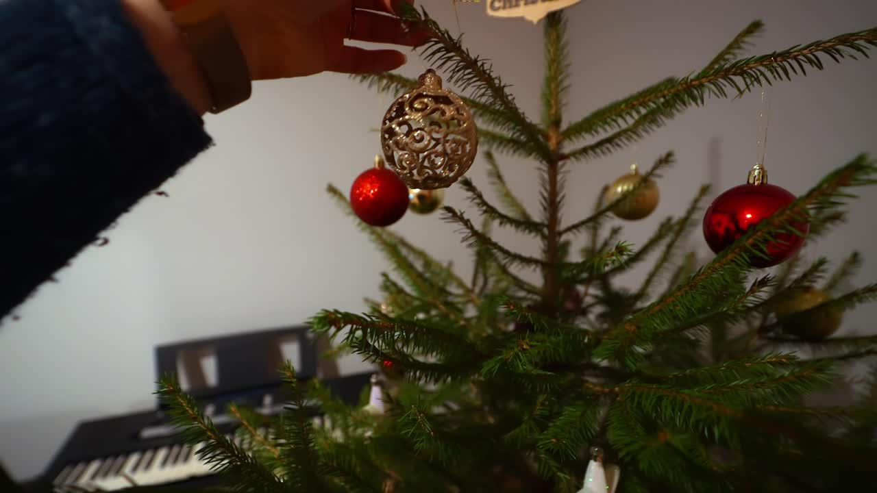 Hand decorating Christmas tree in cozy room, festive and joyful mood
