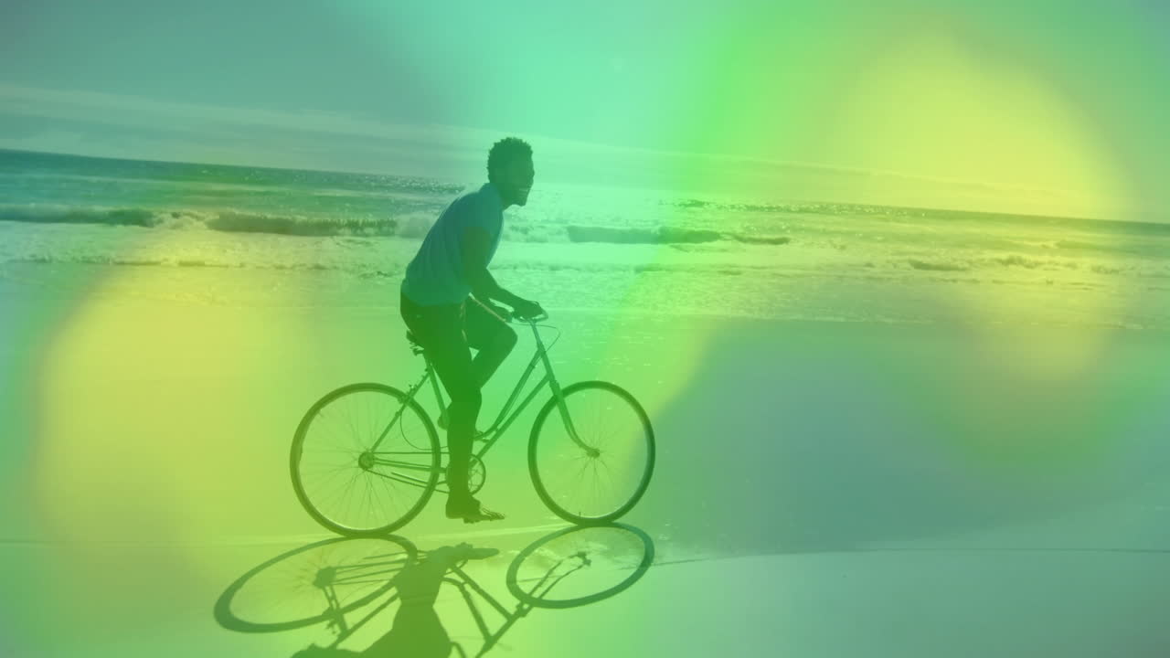 Riding bicycle along beach with colorful animation overlay in background