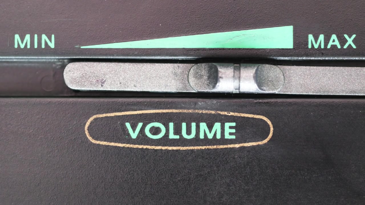 Horizontale close-up van een vinger die een zilveren volumeschuifregelaar van minimum naar maximum en terug beweegt