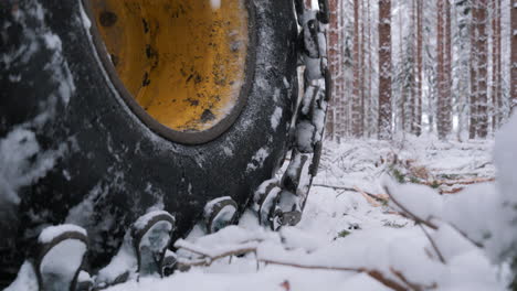 chained excavator wheels move through snowy forest, close up