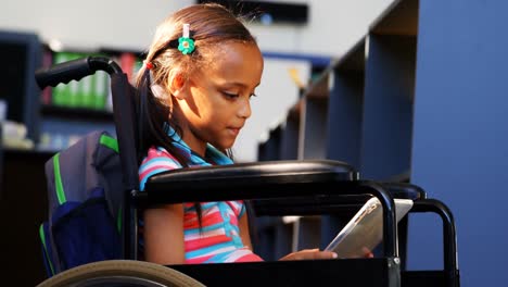 Side-view-of-disabled-African-American-schoolgirl-reading-a-book-in-library-at-school-4k