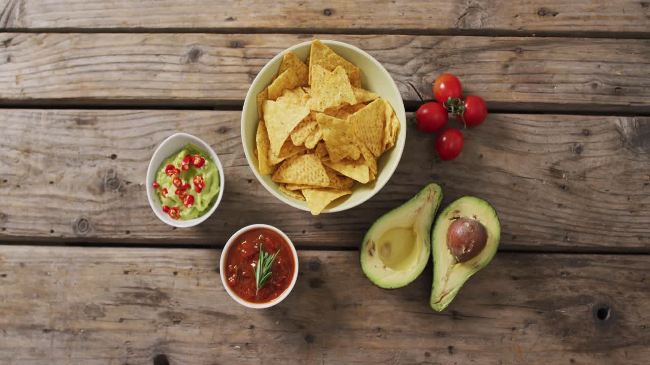 video de chips de tortilla, guacamole y salsa en una superficie de madera
