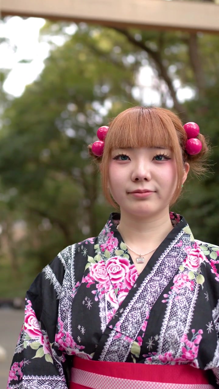 Una donna in yukata tradizionale si trova davanti a un grande torii di legno a Tokyo