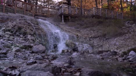 hot water running down waterfall next to rocks inside park with wooden platform