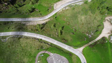 Aerial-of-painted-cyclist-names-on-Passo-Giau-as-car-drives-by,-Giro-d'Itlaia