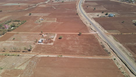 Antena-De-Camión-Que-Sale-De-La-Carretera-Principal-Hacia-Un-Camino-De-Tierra-En-Un-Paisaje-Seco-Y-árido