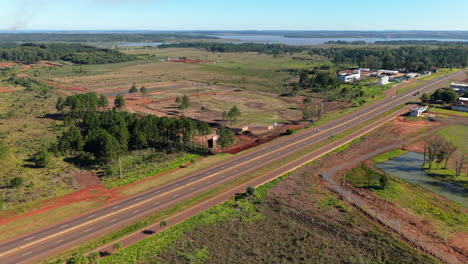 wide aerial clip frames highway worksite near large river, flanked by vegetation under blue skies. ideal for infrastructure or environmental films.