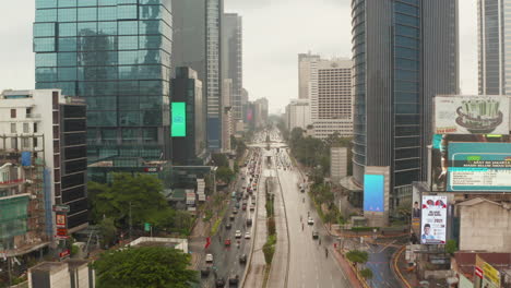 Aerial-retreating-dolly-low-flying-shot-of-vehicles-on-a-multi-lane-road-in-city-center-of-Jakarta-on-a-cloudy-day