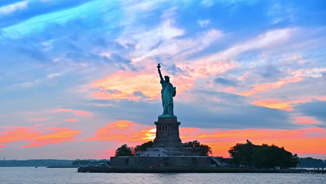 blue and orange cloudy sky at sunset. low angle view at the statue of liberty in new york, usa