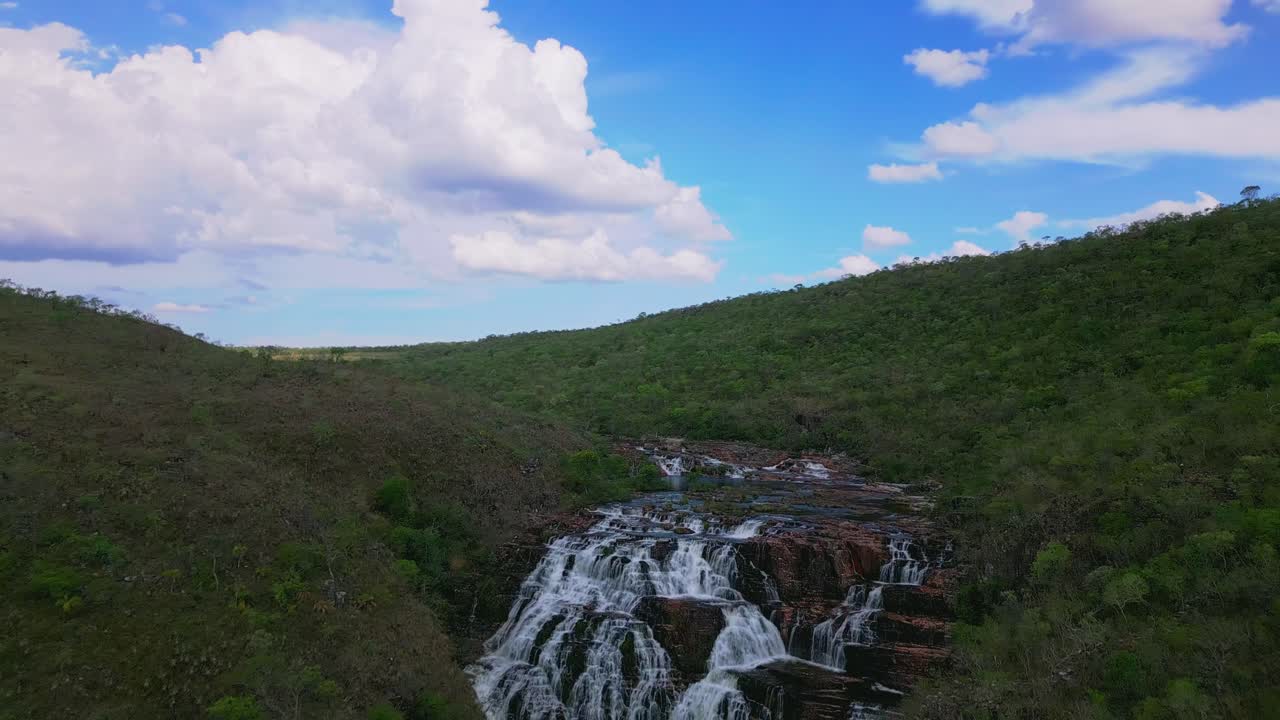 Stunning dos Couros waterfall flowing over multiple rock formations in a lush green valley of Chapada dos Veadeiros national park, Goias, Brazil, Unesco World Heritage Site, drone revealing shot