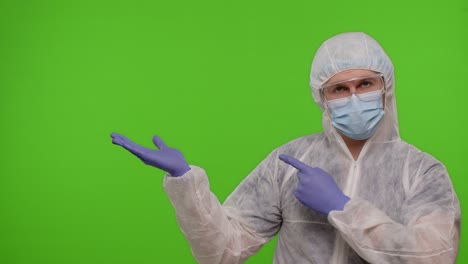 medical doctor in protective ppe suit pointing at left on blank space on chroma key background