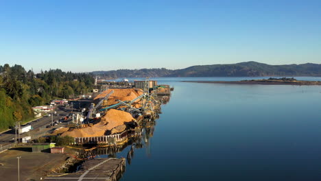 Smooth,-daylight-aerial-dolly-over-lumber-mill,-sawdust-in-Coos-Bay-Oregon