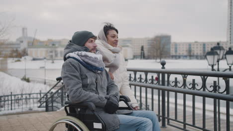 muslim woman and her disable friend looking at something in the distance in city in winter 4