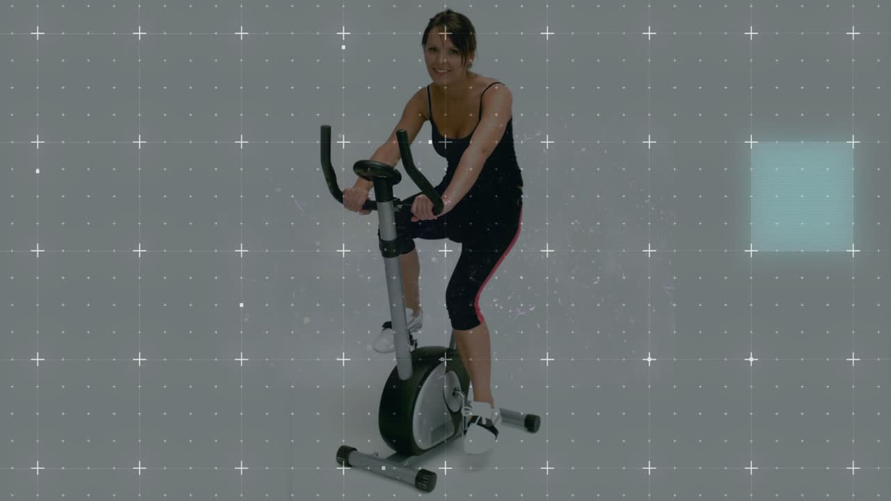Woman pedaling bike in studio on cue, with cyan tiles overlaying scene and lines for fitness