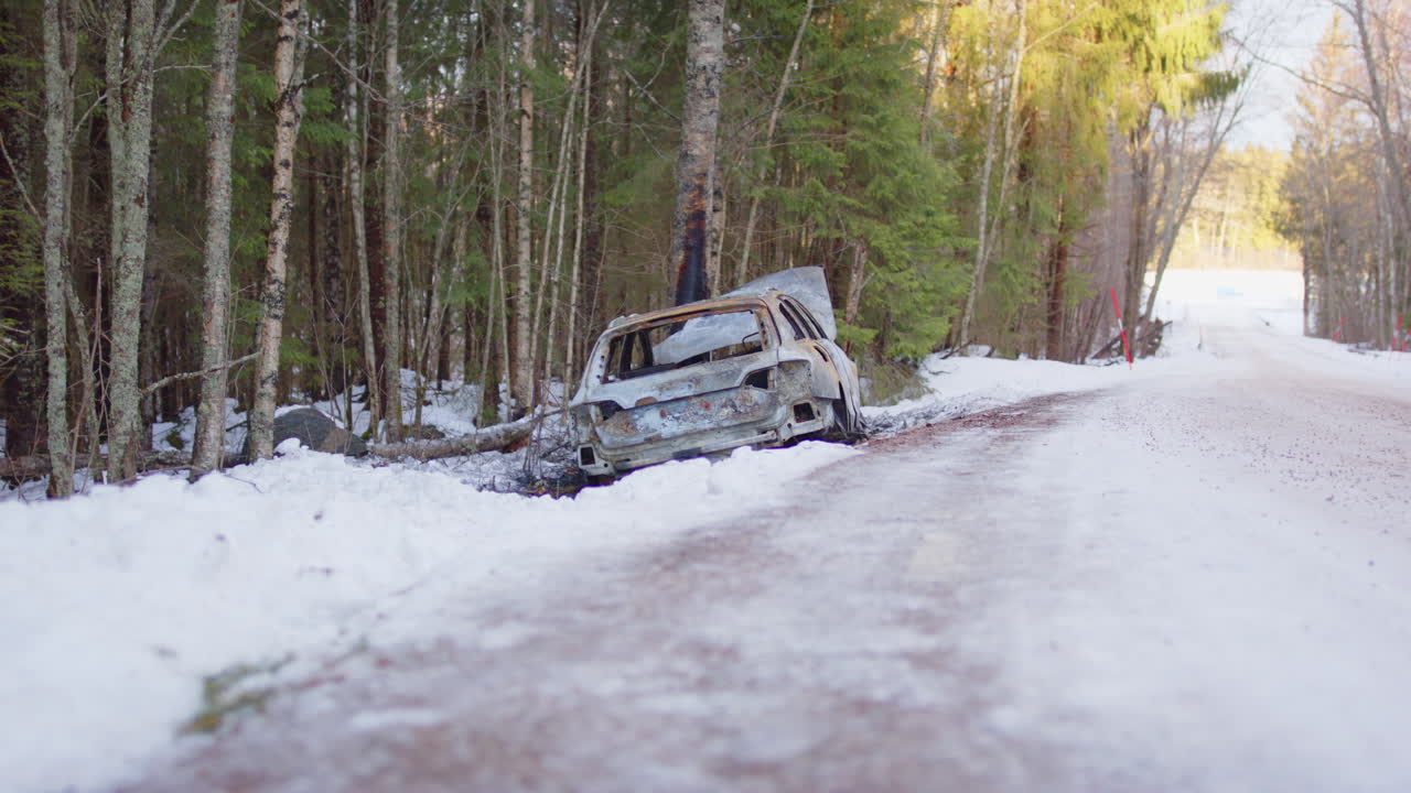 Wrecked and burnt out car crashed into tree after slipping off icy road, slider