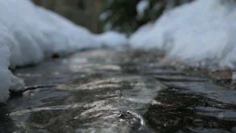Water-streaming-under-ice,-frozen-water-stream-flow-in-winter