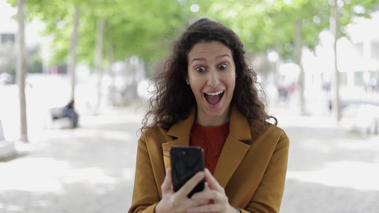 Donna scioccata che usa il cellulare all'aperto