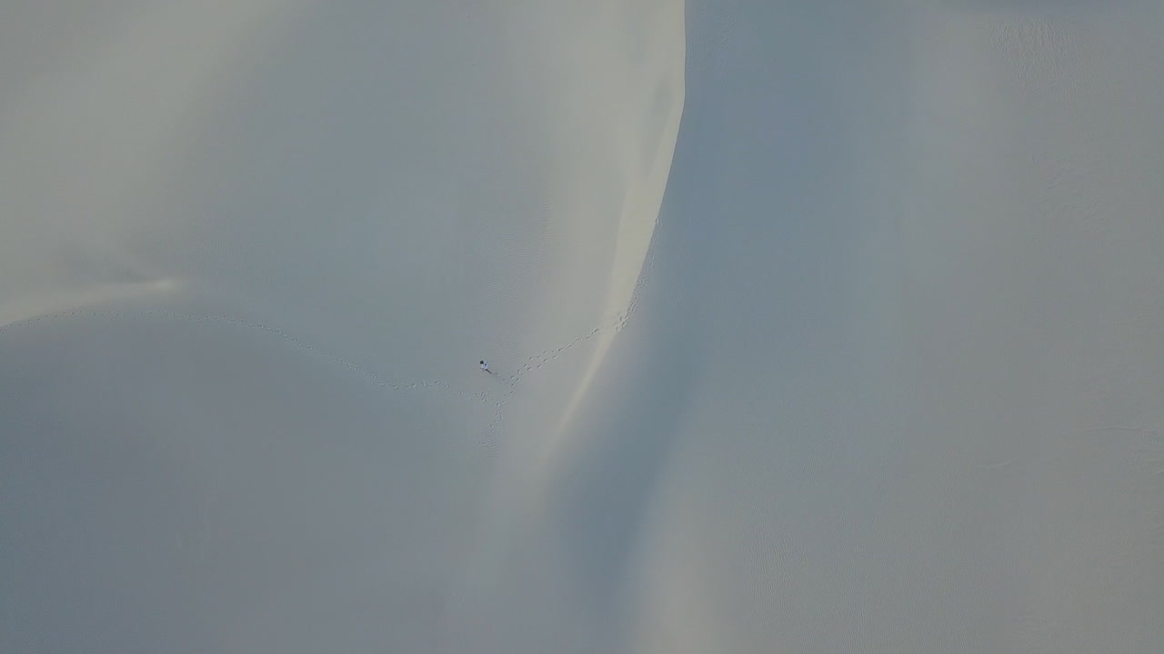 Dramatic aerial of man hiking in snd dunes in South Africa