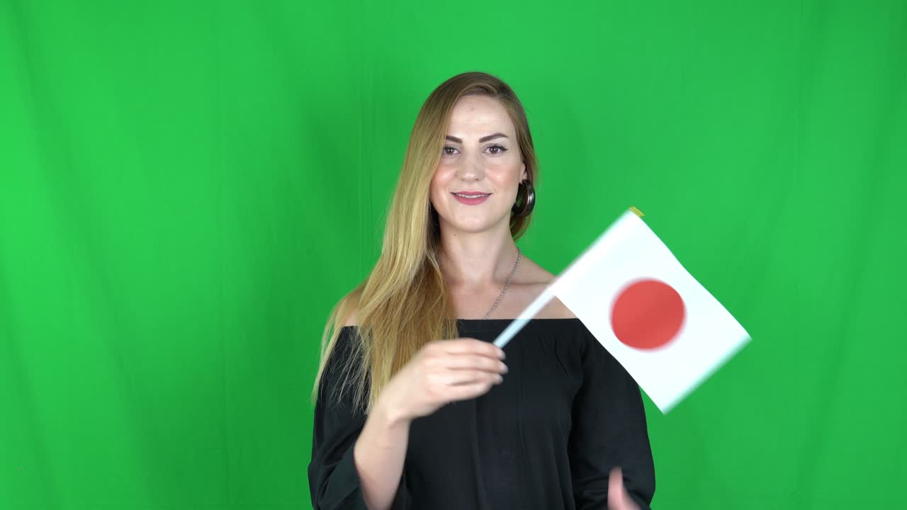 일본 발 앞에서 손을 흔들고 있는 젊은 금발 여성 녹색 스크린, 크로마 키 배경