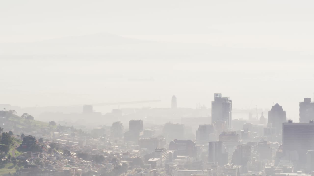 General view of cityscape with multiple modern buildings covered in smog