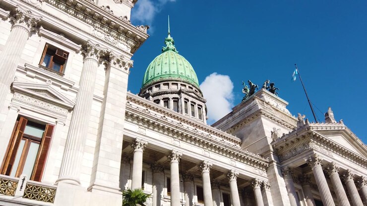 Low angle establishing drone shot of the National Congress of Argentina in Buenos Aires. Highlighting the grand neoclassical columns and the iconic green dome against the horizon