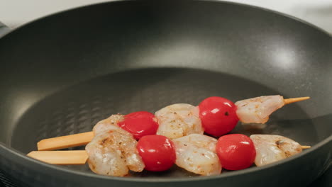 shrimp and tomato skewers cooking in a pan